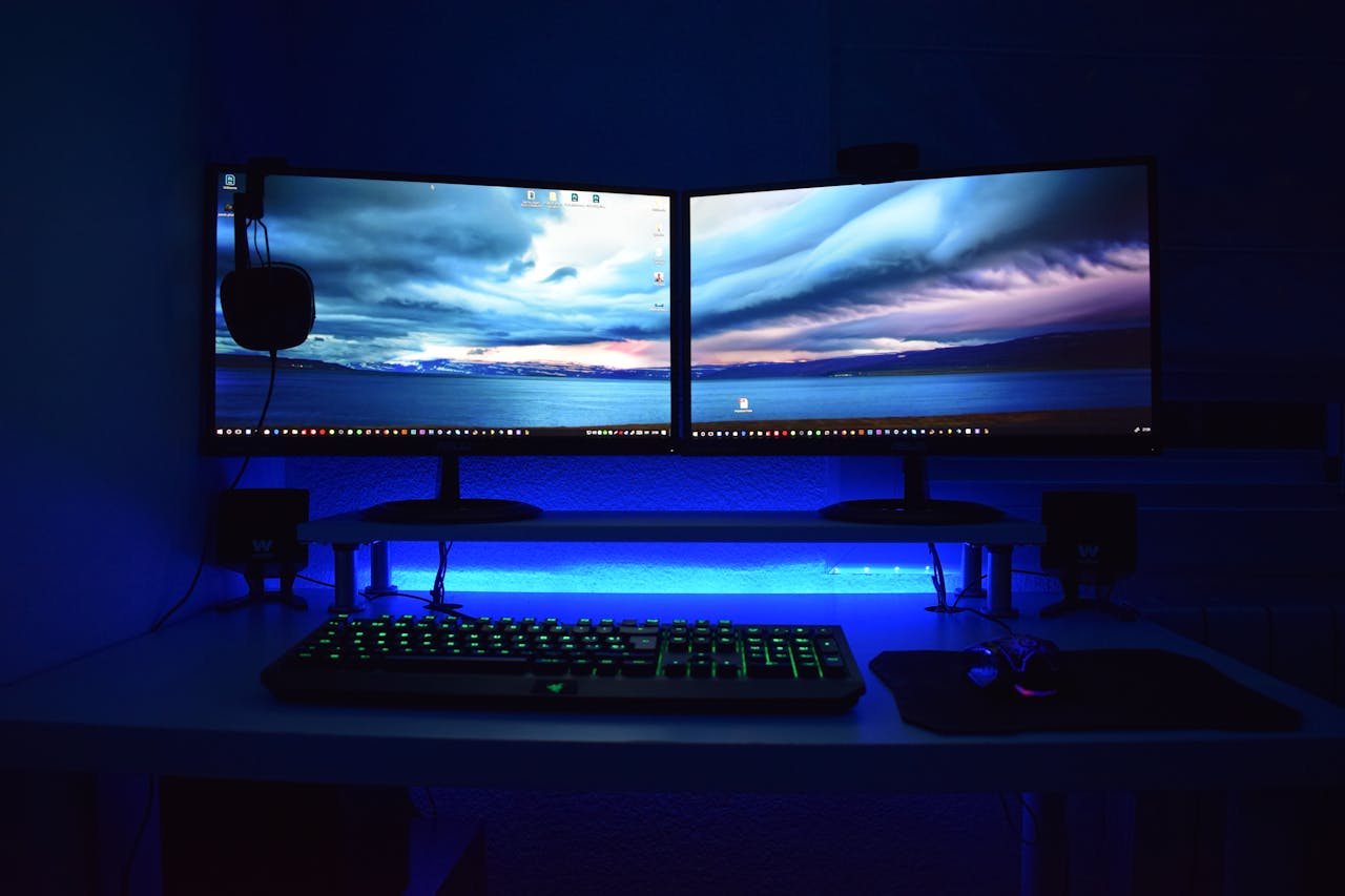 services-04 Dual monitors with blue lighting on a gaming desk setup.